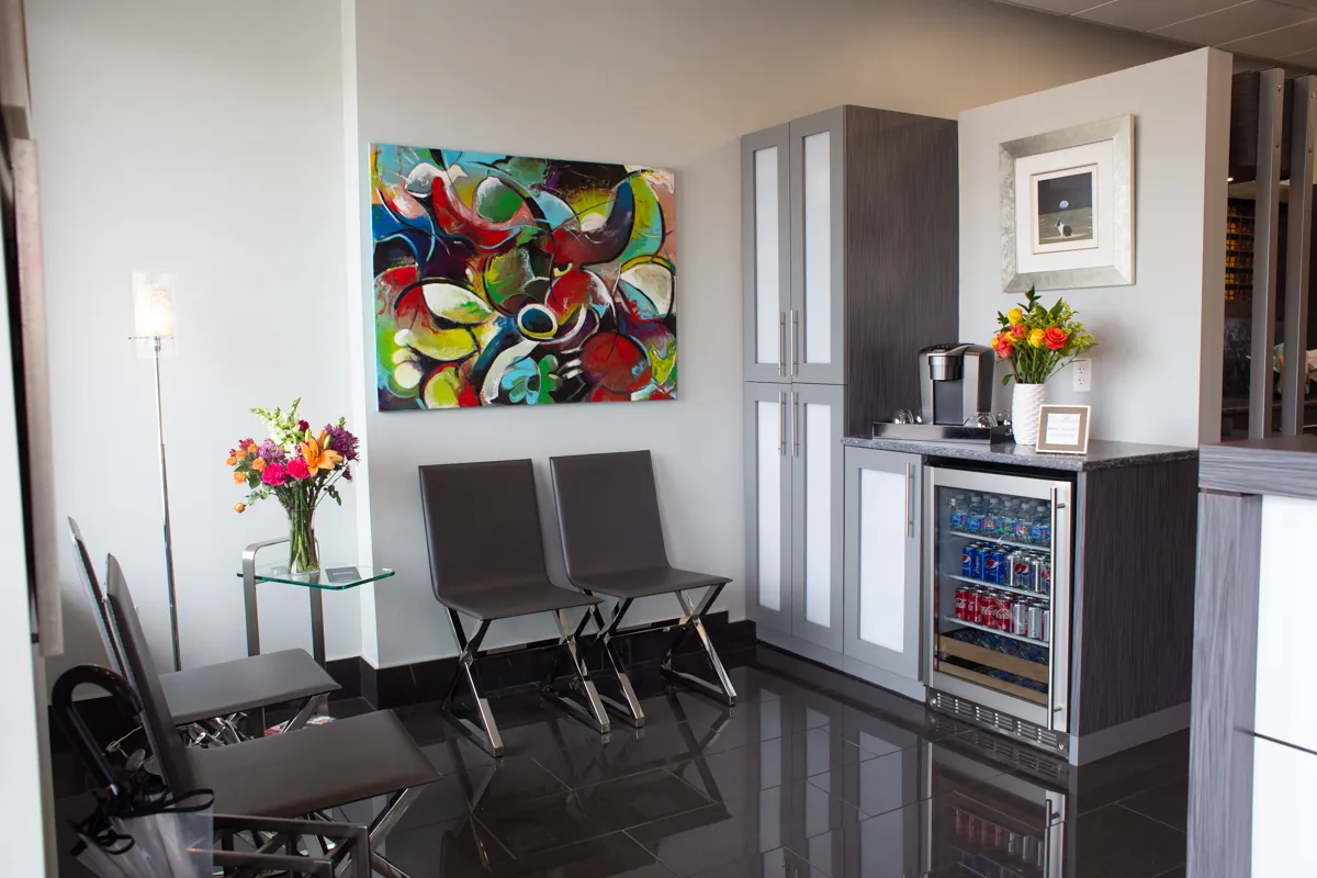 The waiting area at Salon Bastille in Montgomery, Cincinnati, with leather chairs, fresh flowers, a beverage cooler and a large abstract canvas